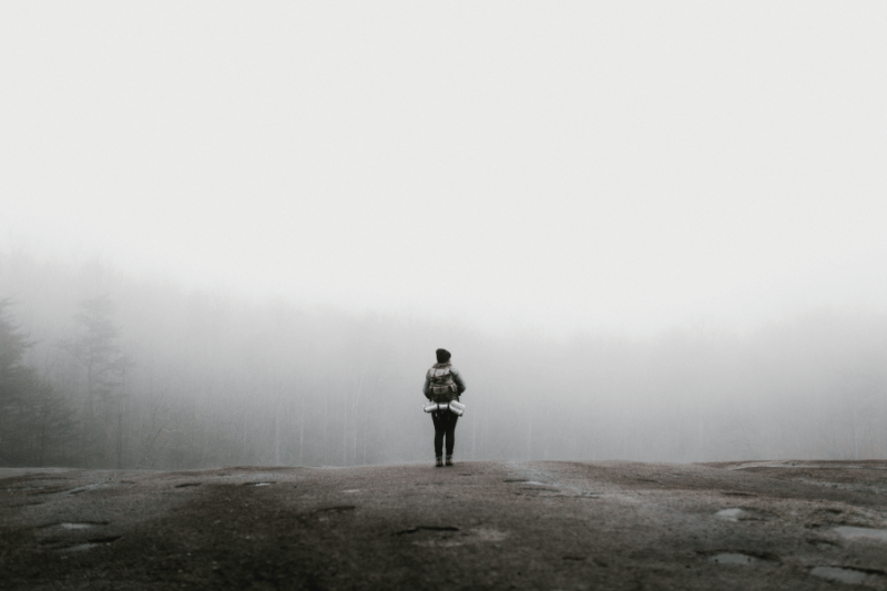 Hiking Woman standing at the edge of a foggy forest