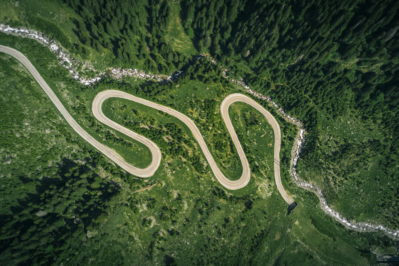 An arial view of a winding road through a green forest